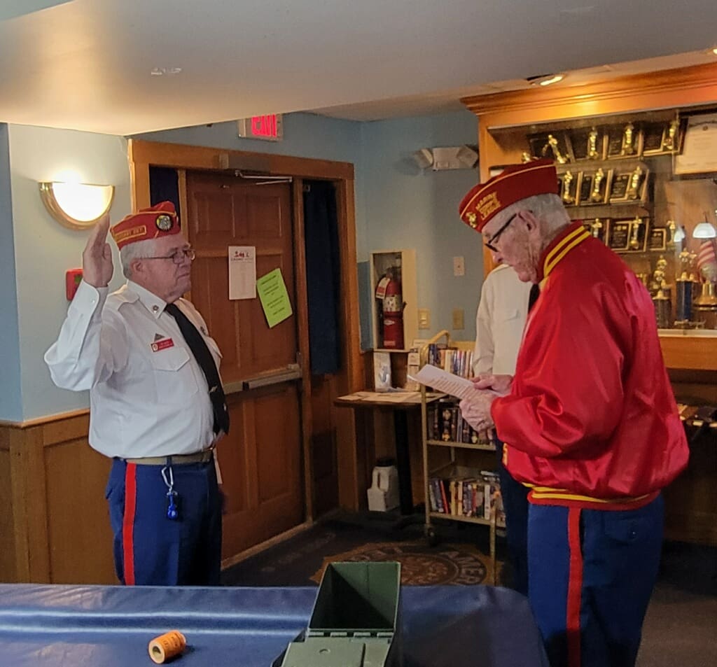 Man in white shirt and red hat raised hand to another man in red hat and red jacket.