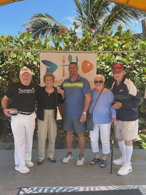 five people stand for a group picture in a FL setting with smiles on their faces